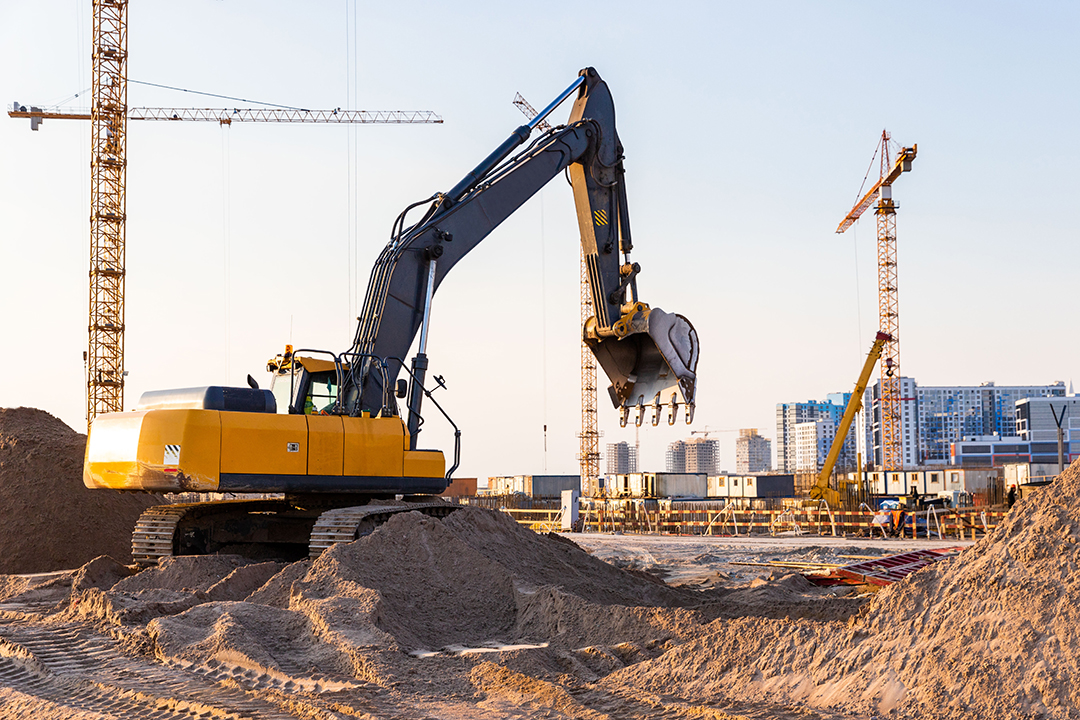 Home group tower cranes and excavator silhouette at construction site